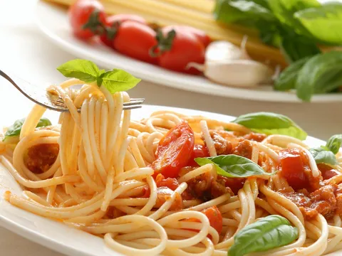 Espaguetis con tomate casero y hojas de albahaca fresca