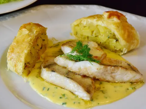 Lomos de merluza en salsa verde con patatas en un plato blanco