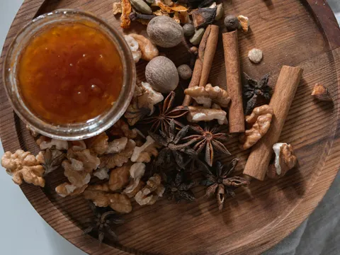 Especias enteras (canela, anís estrellado, nuez moscada) junto a un tarro de mermelada de higos