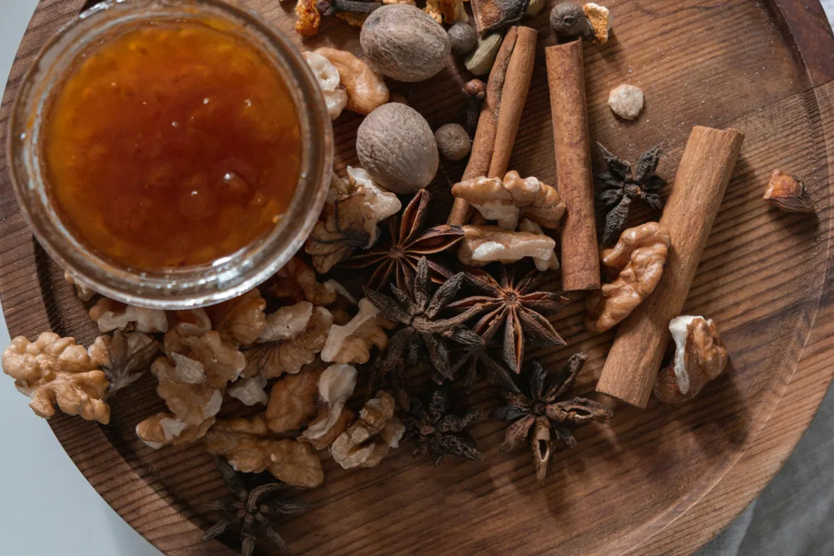 Especias enteras (canela, anís estrellado, nuez moscada) junto a un tarro de mermelada de higos