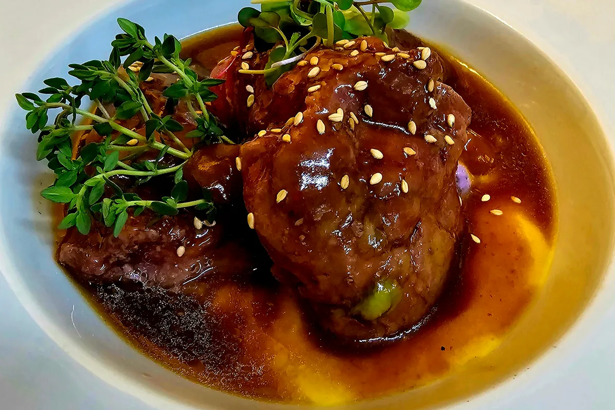 Carrilleras de cerdo en salsa servidas con la salsa de verduras y vino