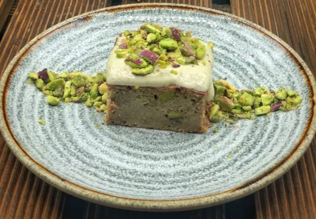 Porción de brownie de pistachos con cobertura blanca y pistacho picado