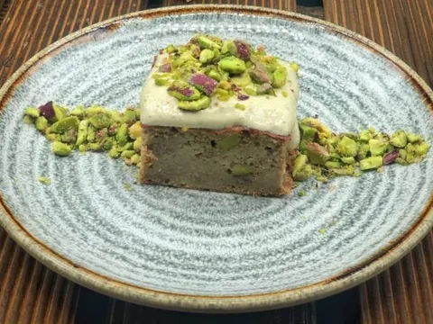 Porción de brownie de pistachos con cobertura blanca y pistacho picado