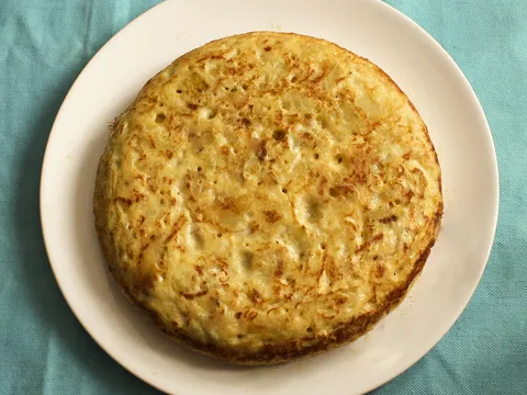 Tortilla de patatas con calabacín entera en un plato blanco