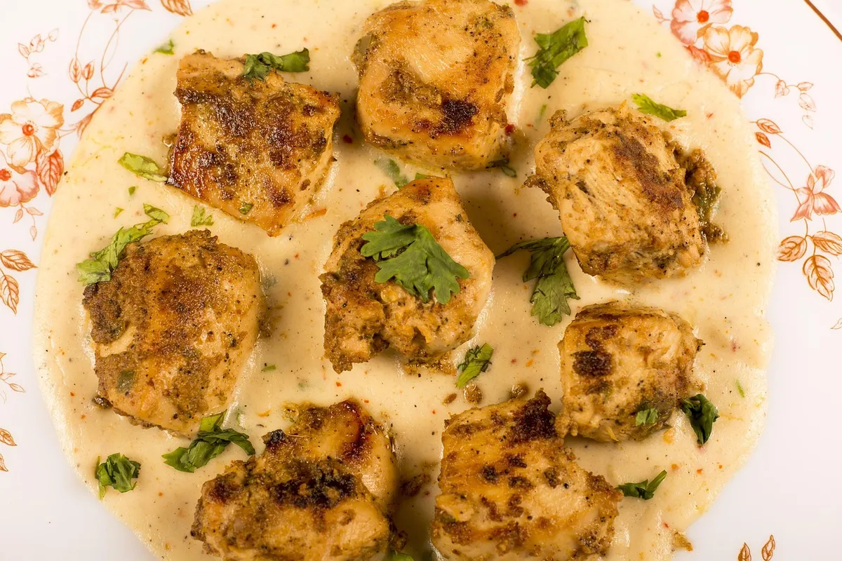 Trozos de pollo bañados en salsa cremosa de almendras servidos en un plato