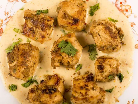 Trozos de pollo bañados en salsa cremosa de almendras servidos en un plato