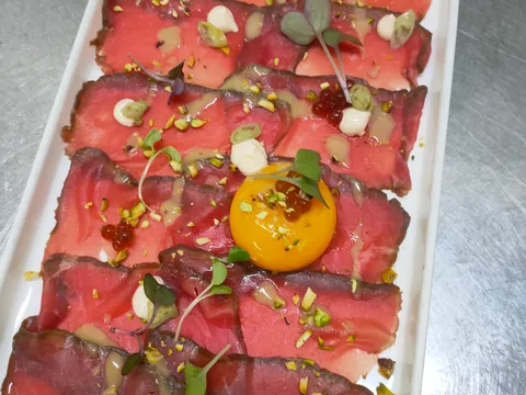 Carpaccio de wagyu en lonchas finas con pistacho picado y yema de huevo