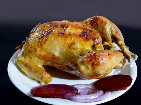 Pollo entero rustido y dorado servido en una fuente