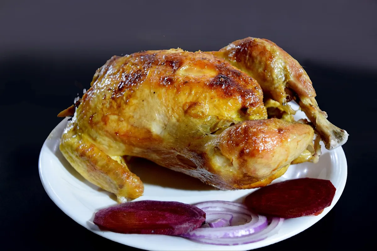 Pollo entero rustido y dorado servido en una fuente